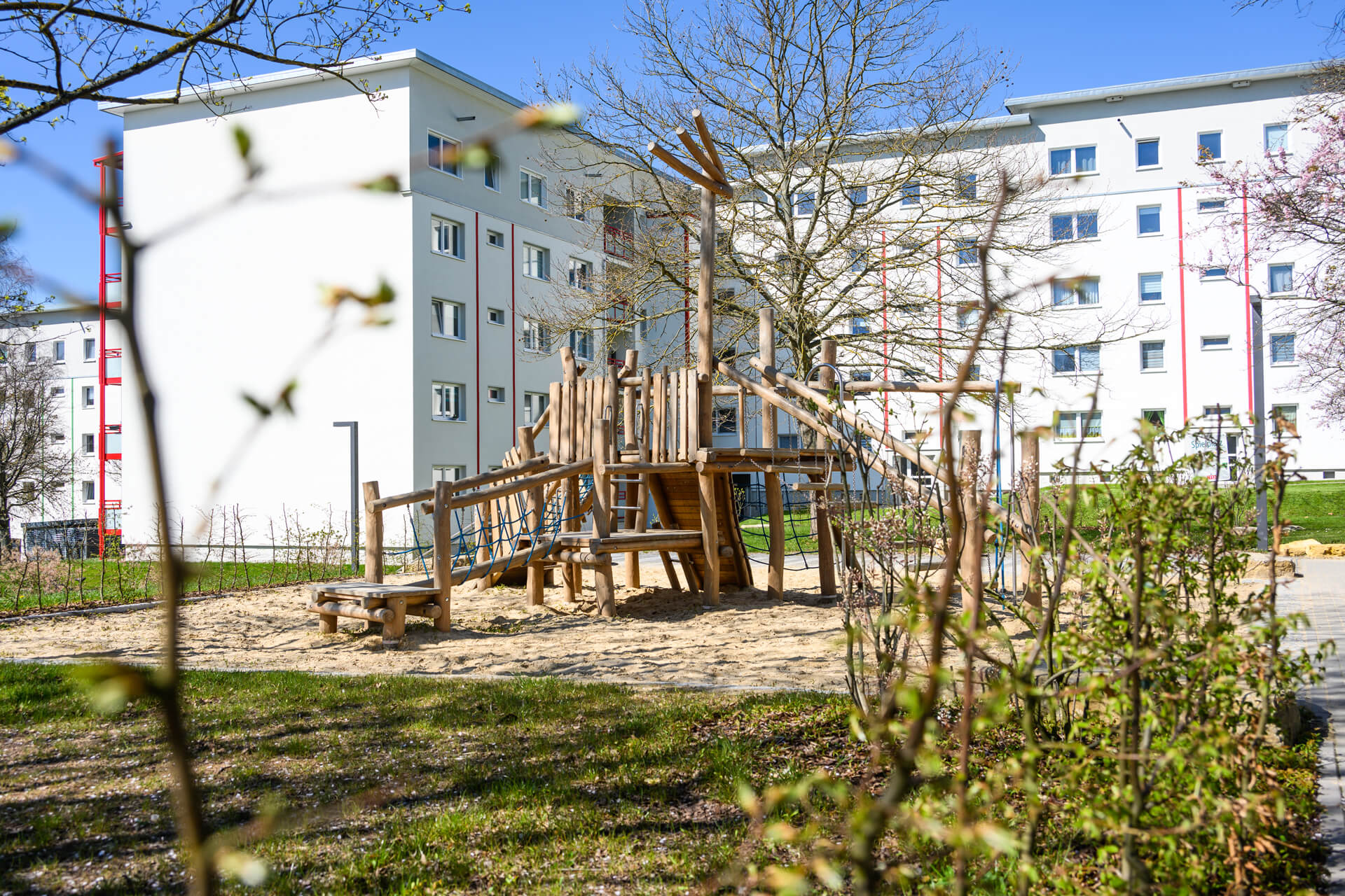 Kinderspielplatz mit Holzklettergerüst und Sandbereich vor Wohngebäuden der KOWO in Heilbad Heiligenstadt
