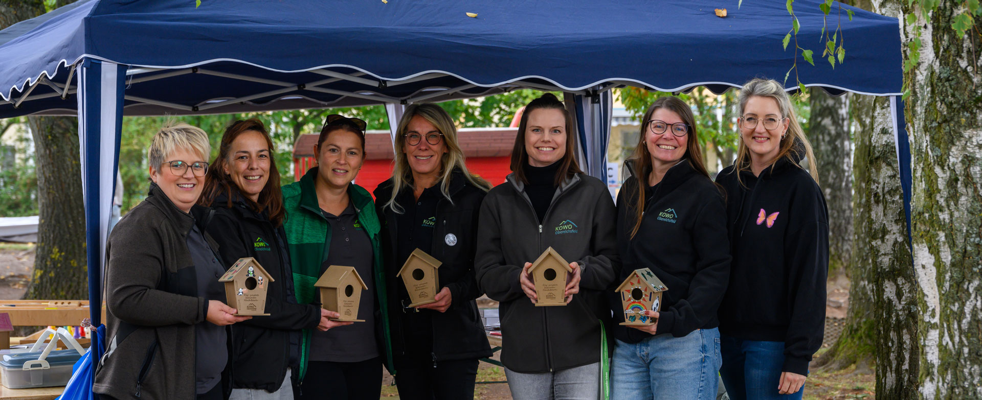 Fünf KOWO-Mitarbeiterinnen aus Heilbad Heiligenstadt präsentieren selbst gebaute Vogelhäuschen bei einer Gemeinschaftsaktion.